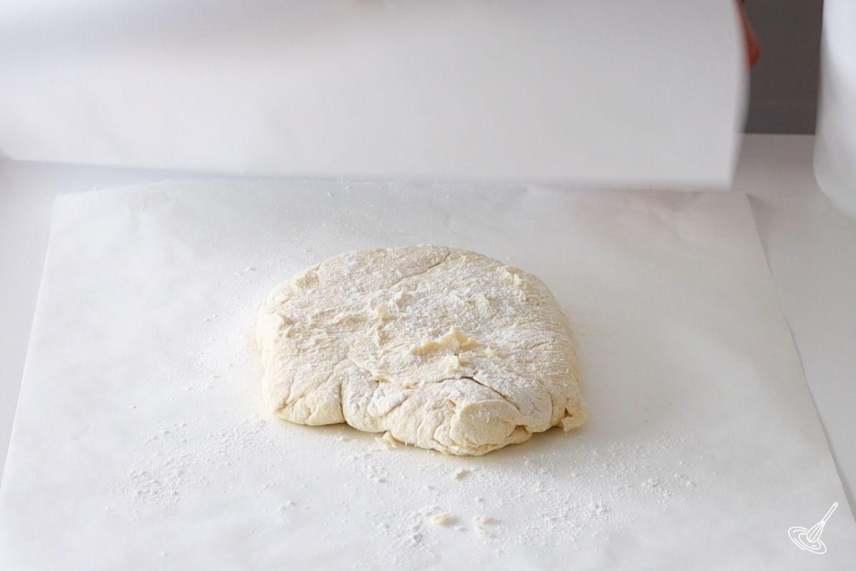 A disk of pie dough on parchment paper.