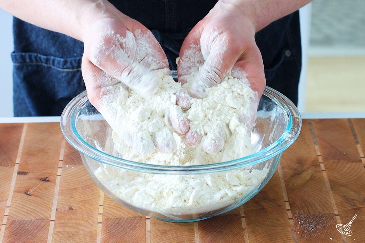 Someone using their hands to cut butter into four.