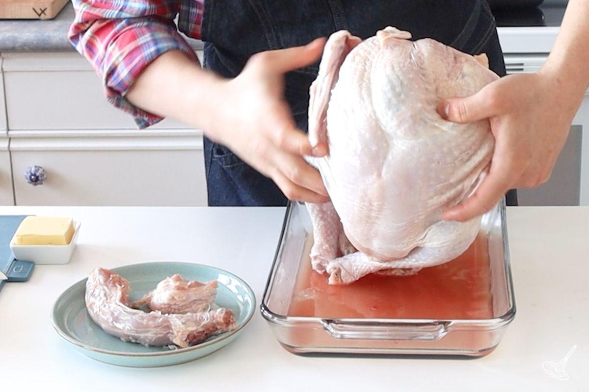 Someone removing draining the turkey roast from its thawing liquids. 