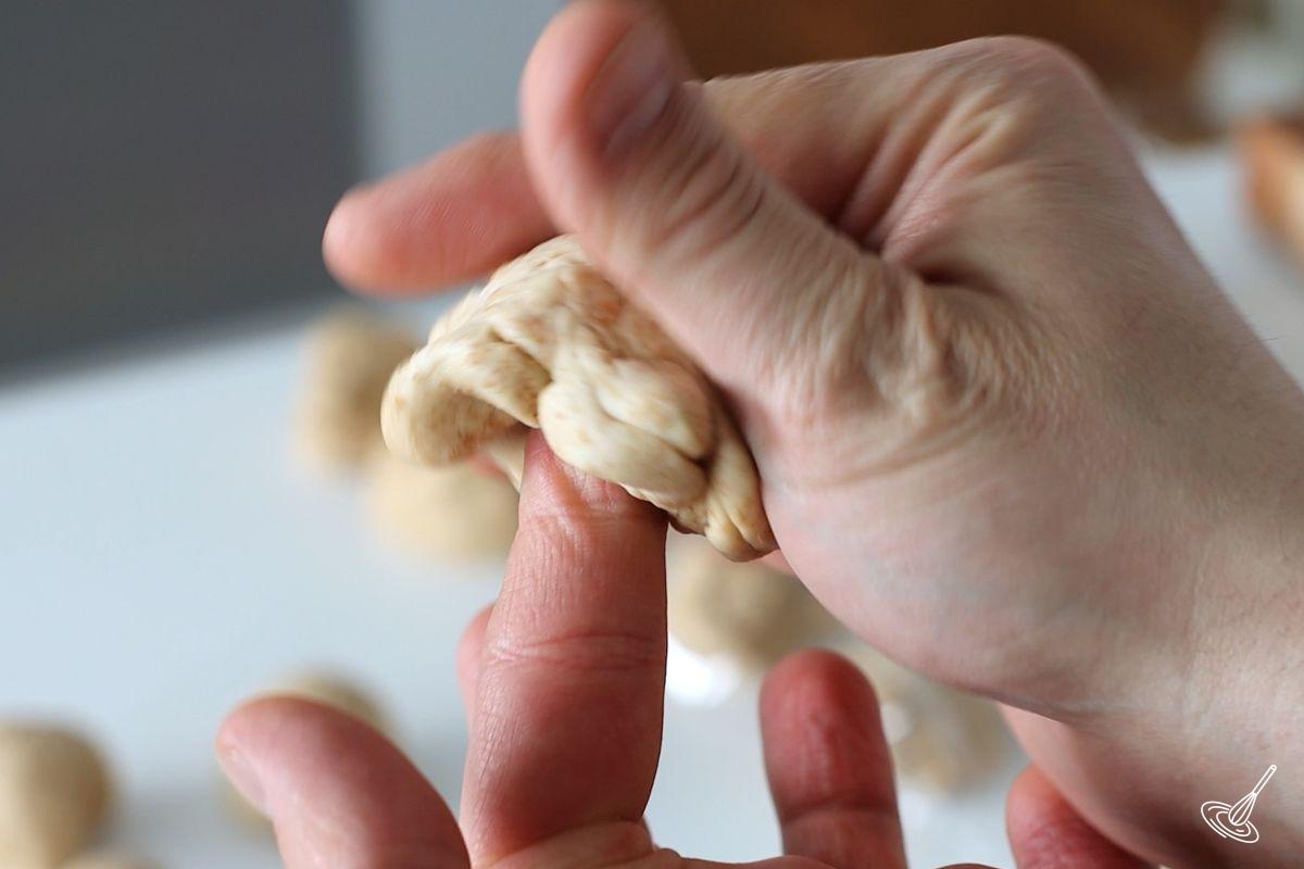 Someone using their fingers to shape a ball of bread dough.