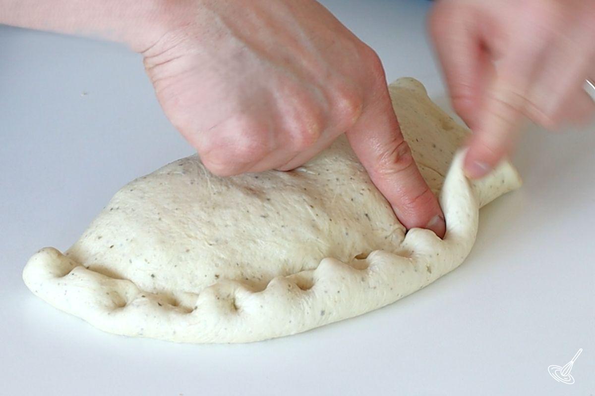 Someone pinching shut a calzone. 