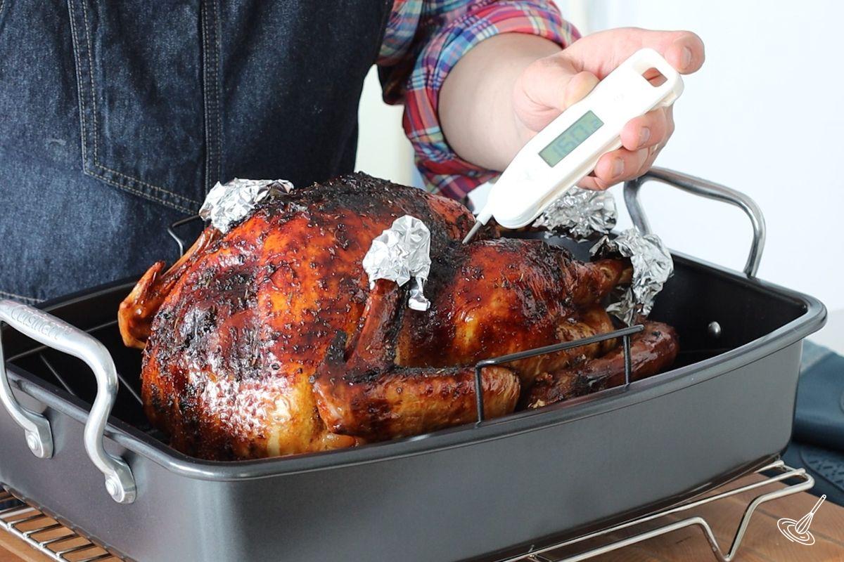 Someone using a probe thermometer to check the internal temperature of the roasted turkey. 