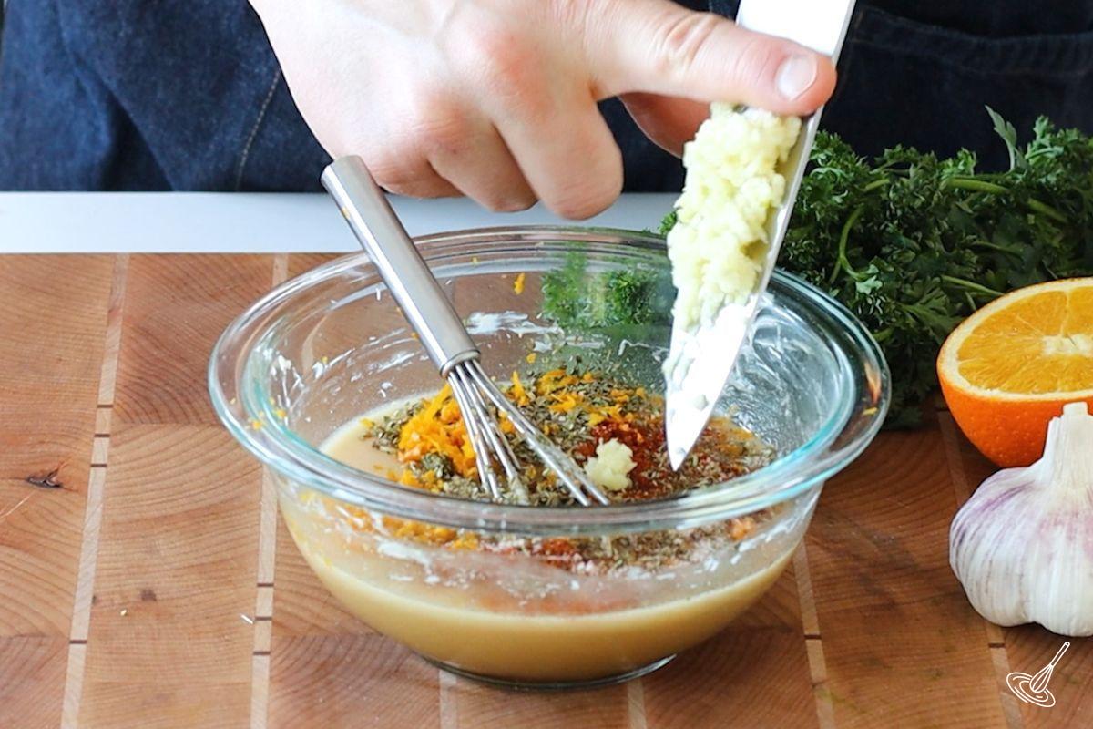 Someone adding chopped garlic to a butter and maple mixture. 