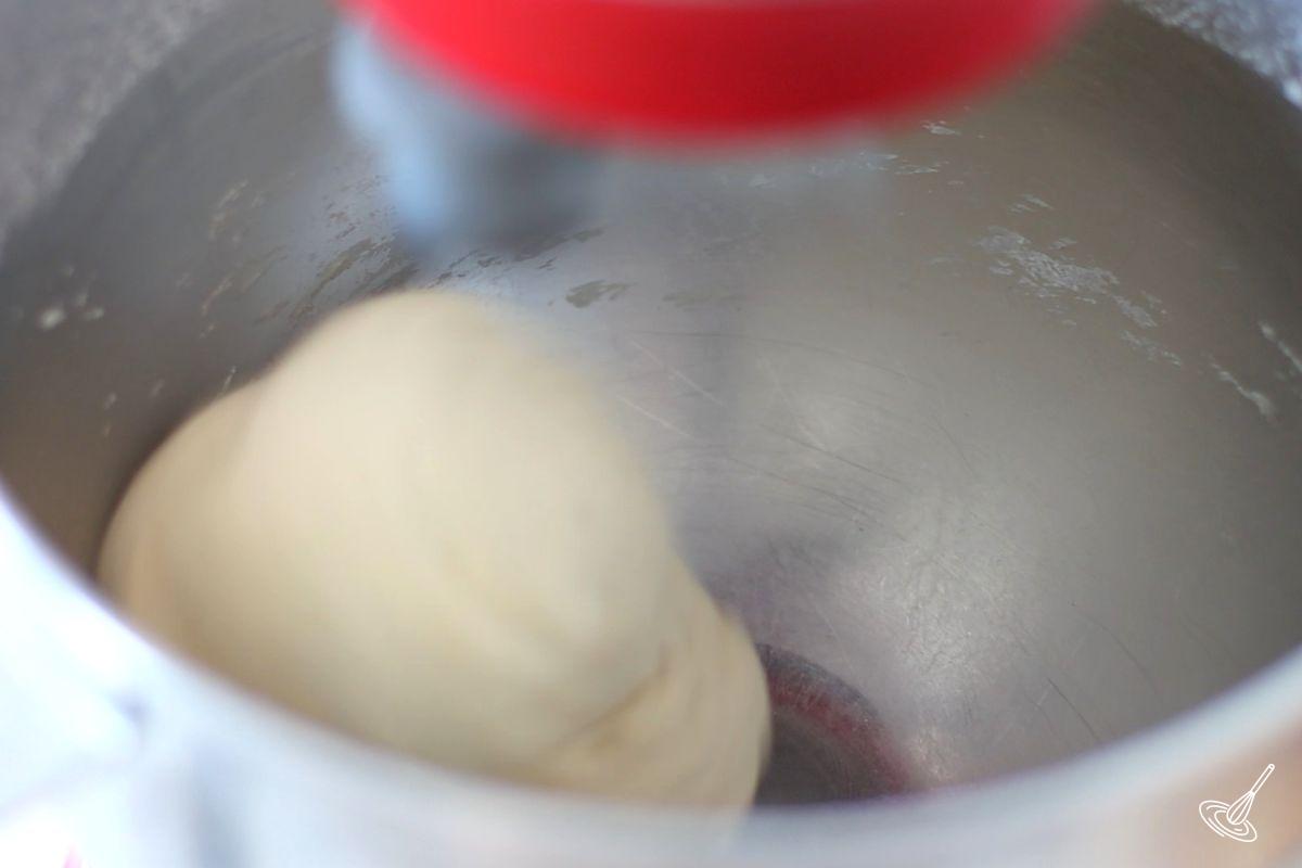 A pizza dough being mixed in a stand mizer.