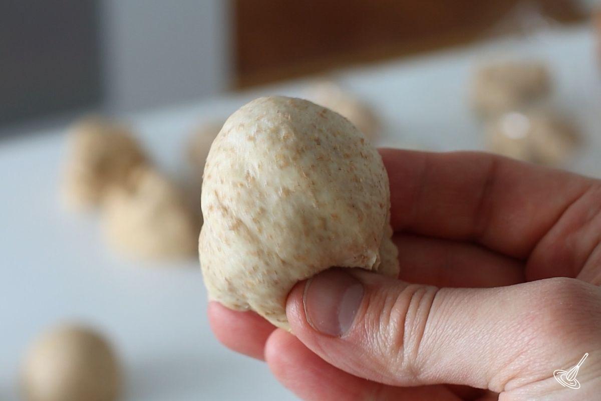 Someone pinching together a small ball of dough.