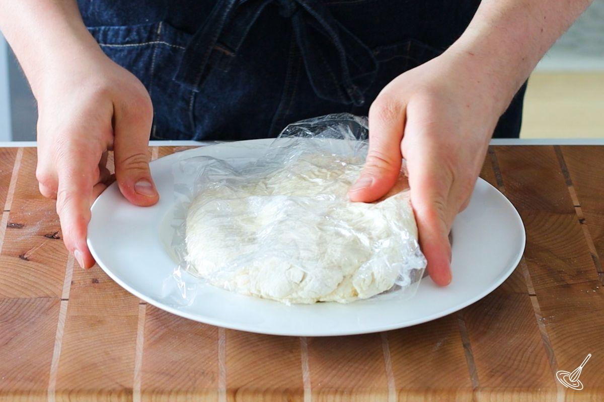 Someone placing a disk of pie dough on a plate.