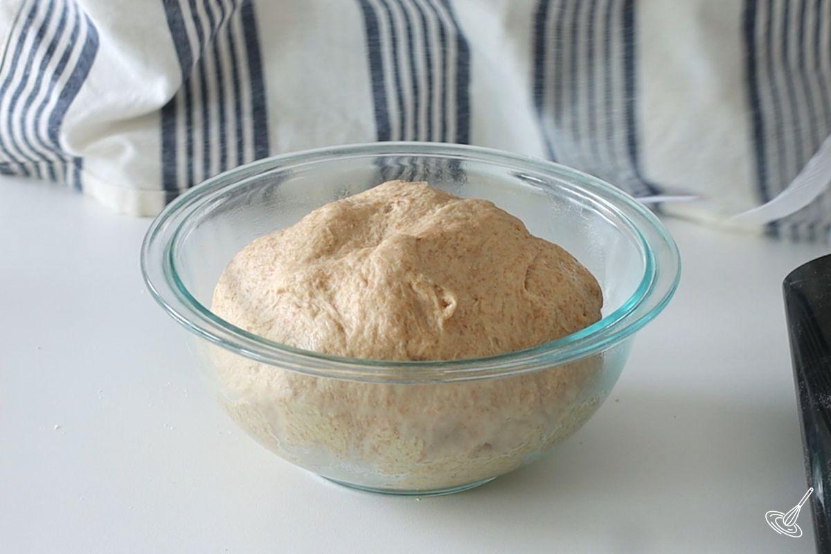 A ball of honey whole wheat dough in a glass bowl. 