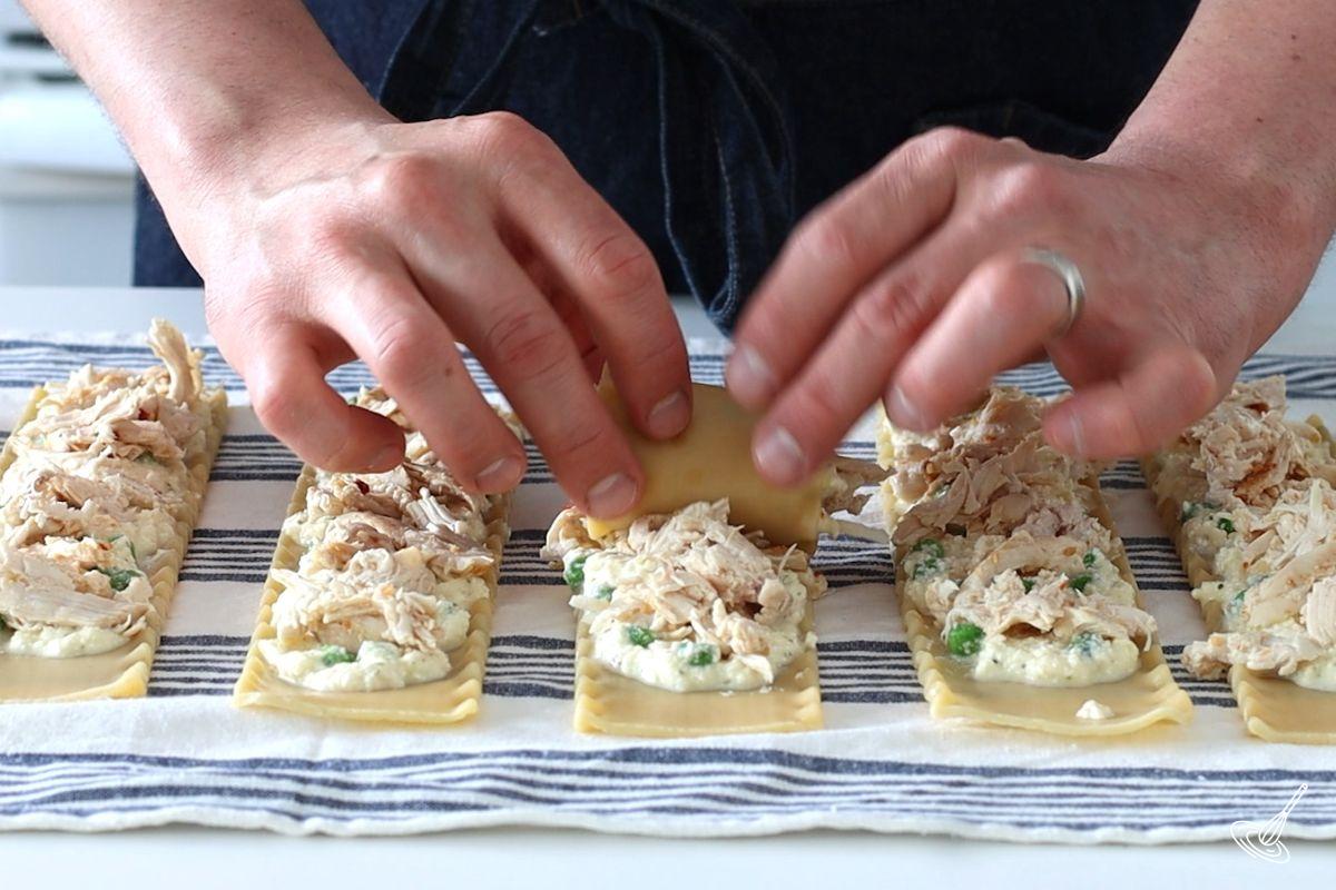 Someone rolling up a Turkey Alfredo Lasagna, 