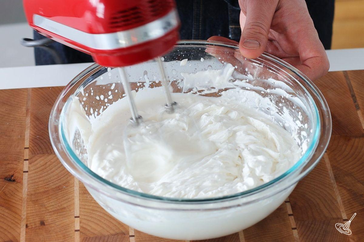Someone using a hand blender to whip up cream. 