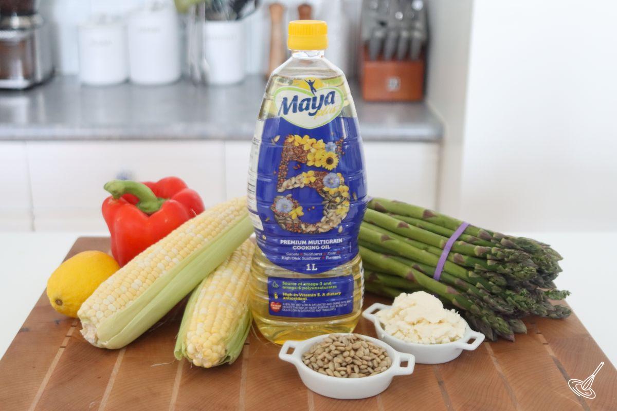 Ingredients on a cutting board, including corn, asparagus, bell pepper, and lemon. 