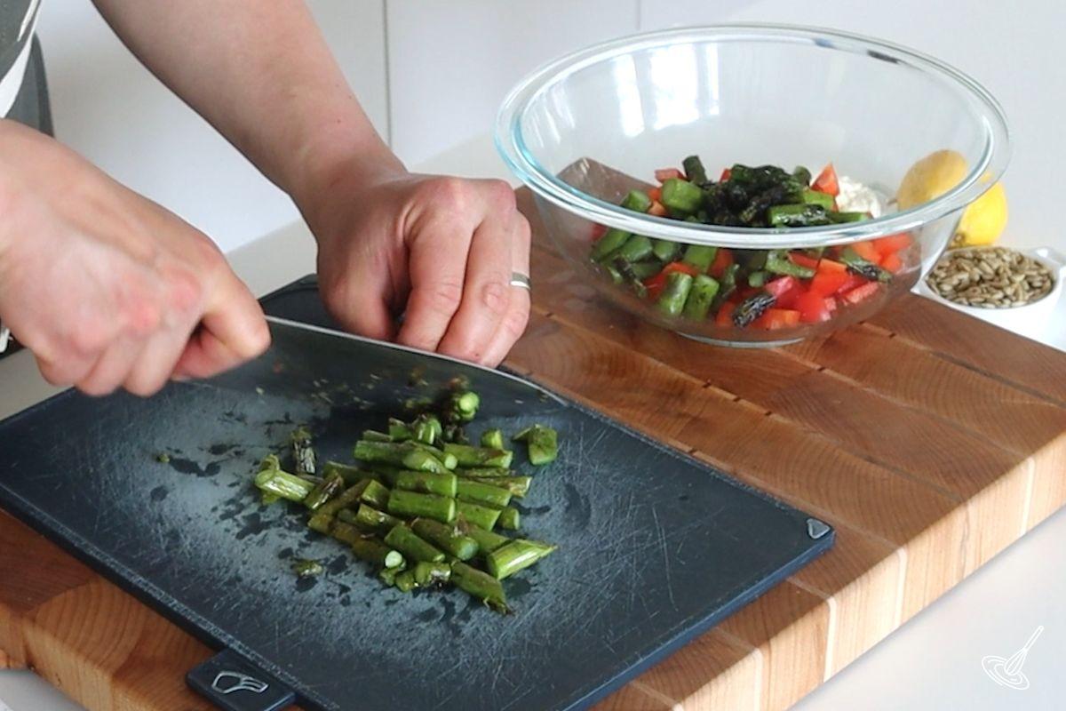 Someone cutting roasted asparagus into bite-sized pieces.