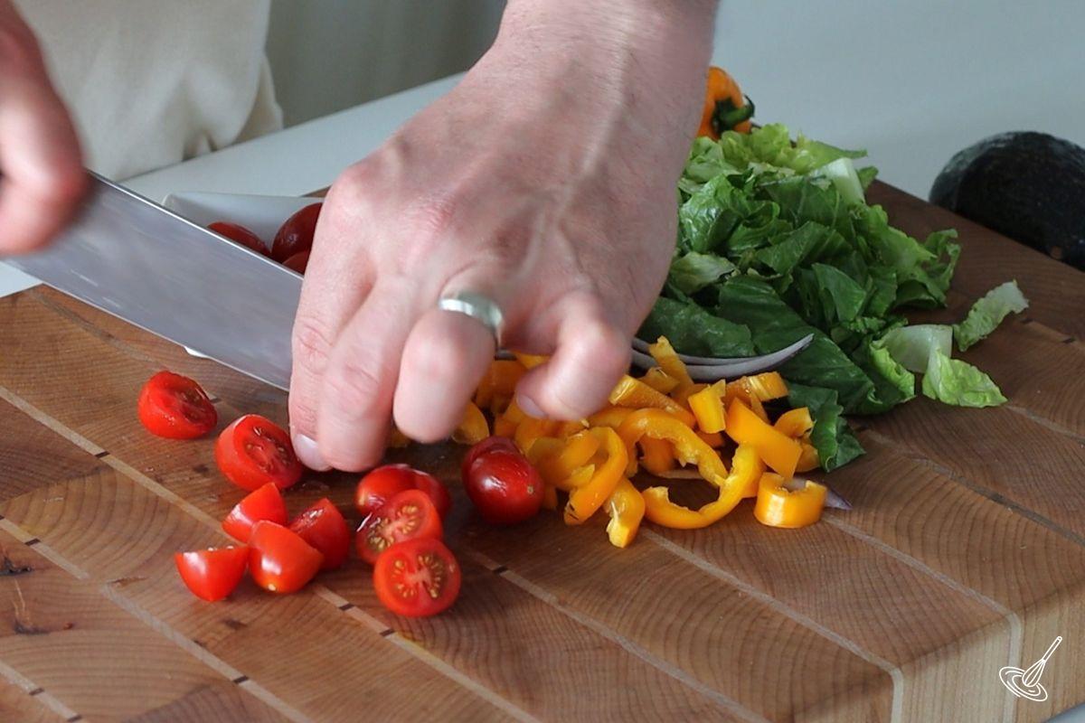 Someone cutting cherry tomatoes in half. 