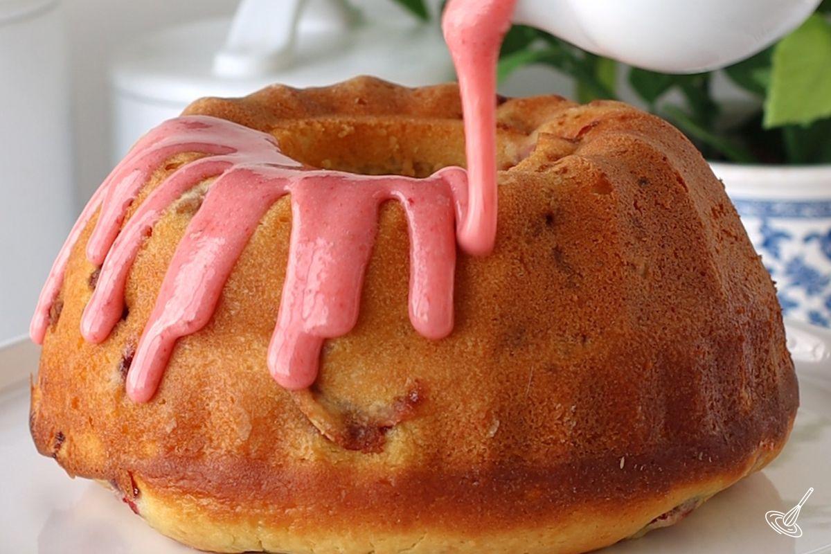 Someone pouring strawberry icing over a cooled Strawberry Lemonade Bundt Cake.