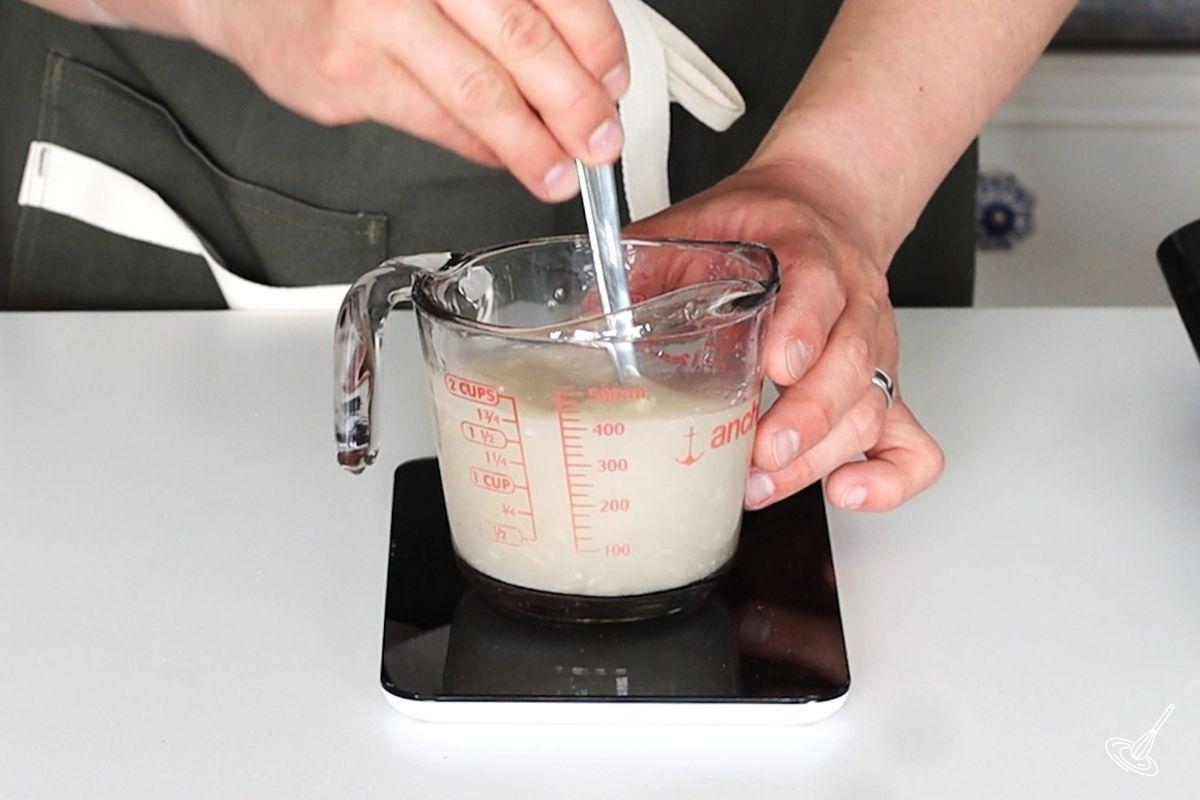 Someone stirring a yeast water mixture.