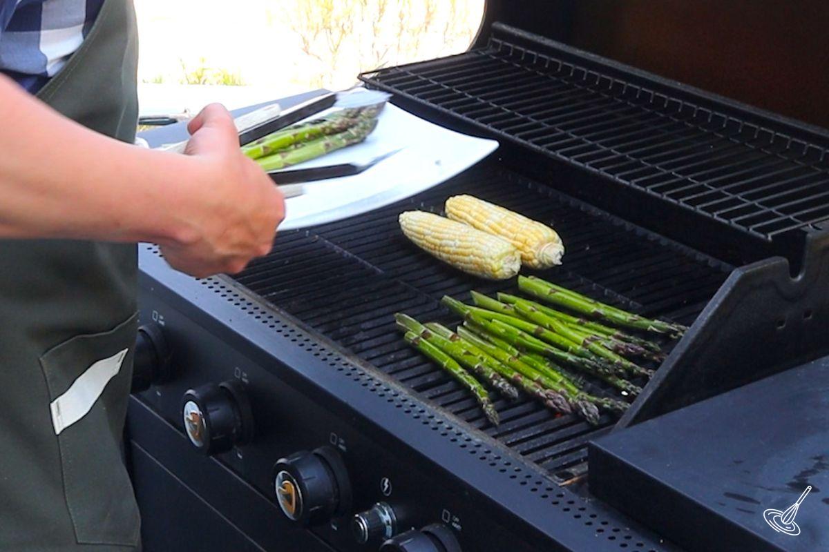 Someone grilling asparagus and corn on the BBQ.