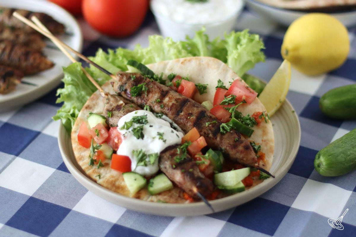 Ground Turkey kofta skewers on a pita bread with toppings.