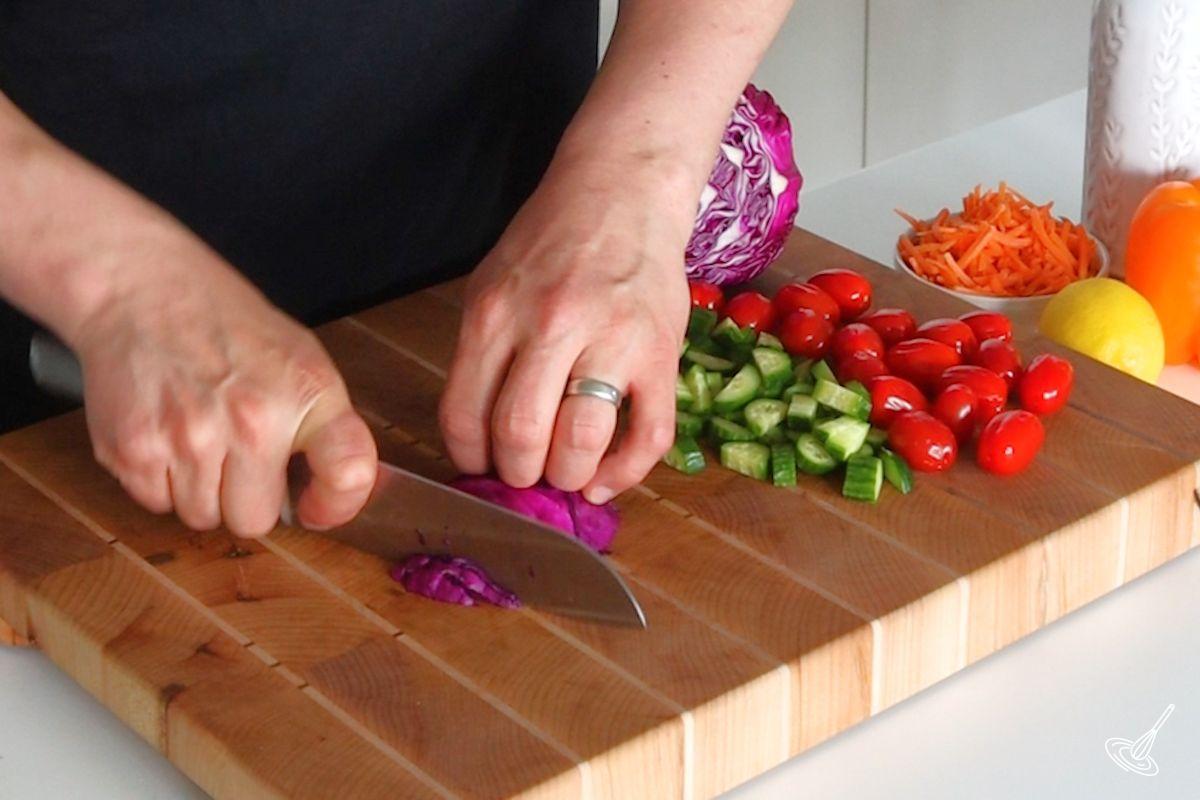 Someone using a knife to shred red cabbage.