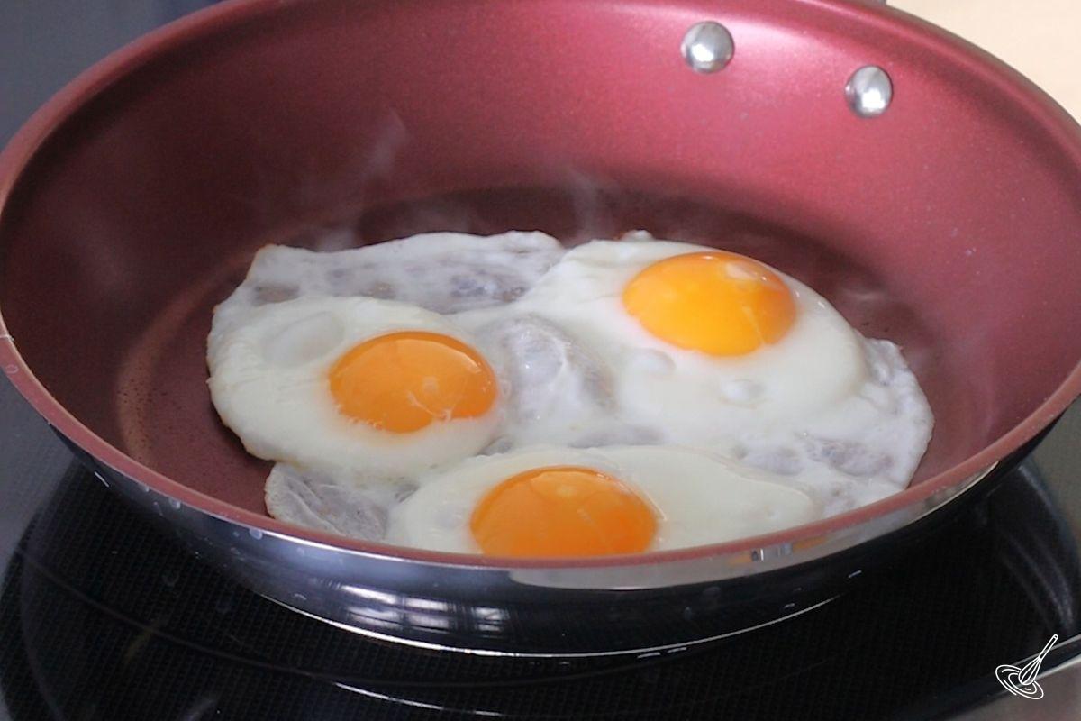 Sunny side up eggs cooking in a frying pan. 