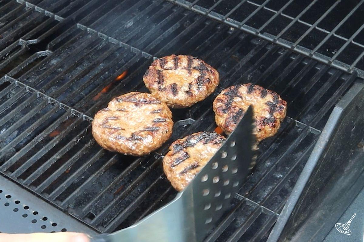 Hamburger patties cooking on a BBQ grill.