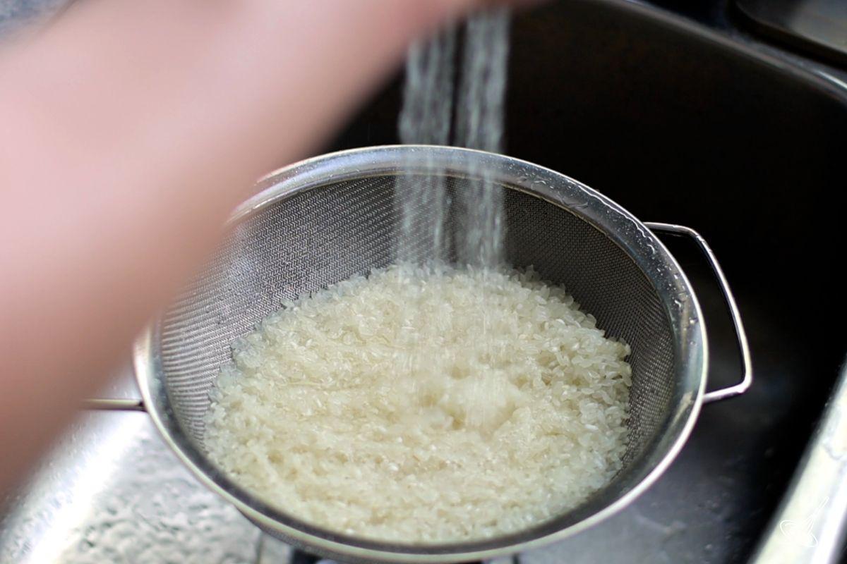 Someone rinsing rice in a colander. 
