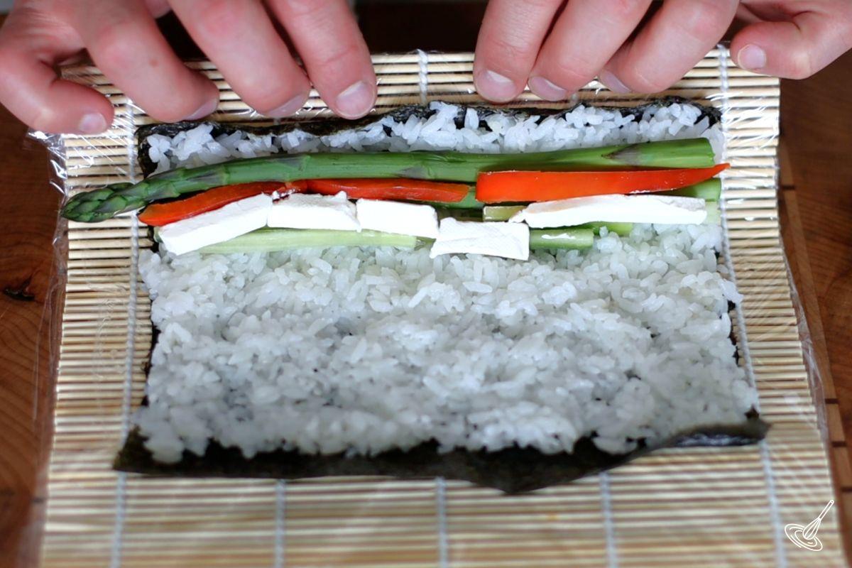 Someone rolling up an Asparagus Roll Sushi.