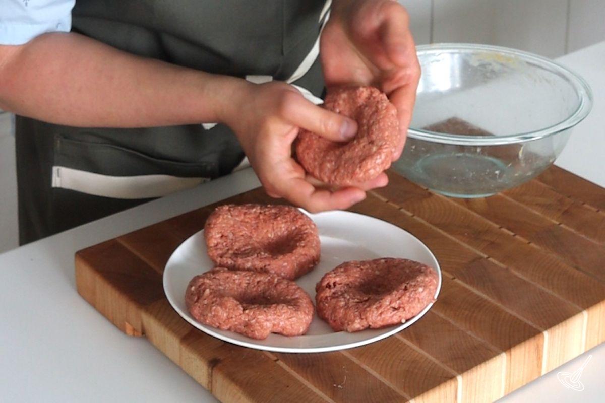 Someone shaping beef hamburger patties.
