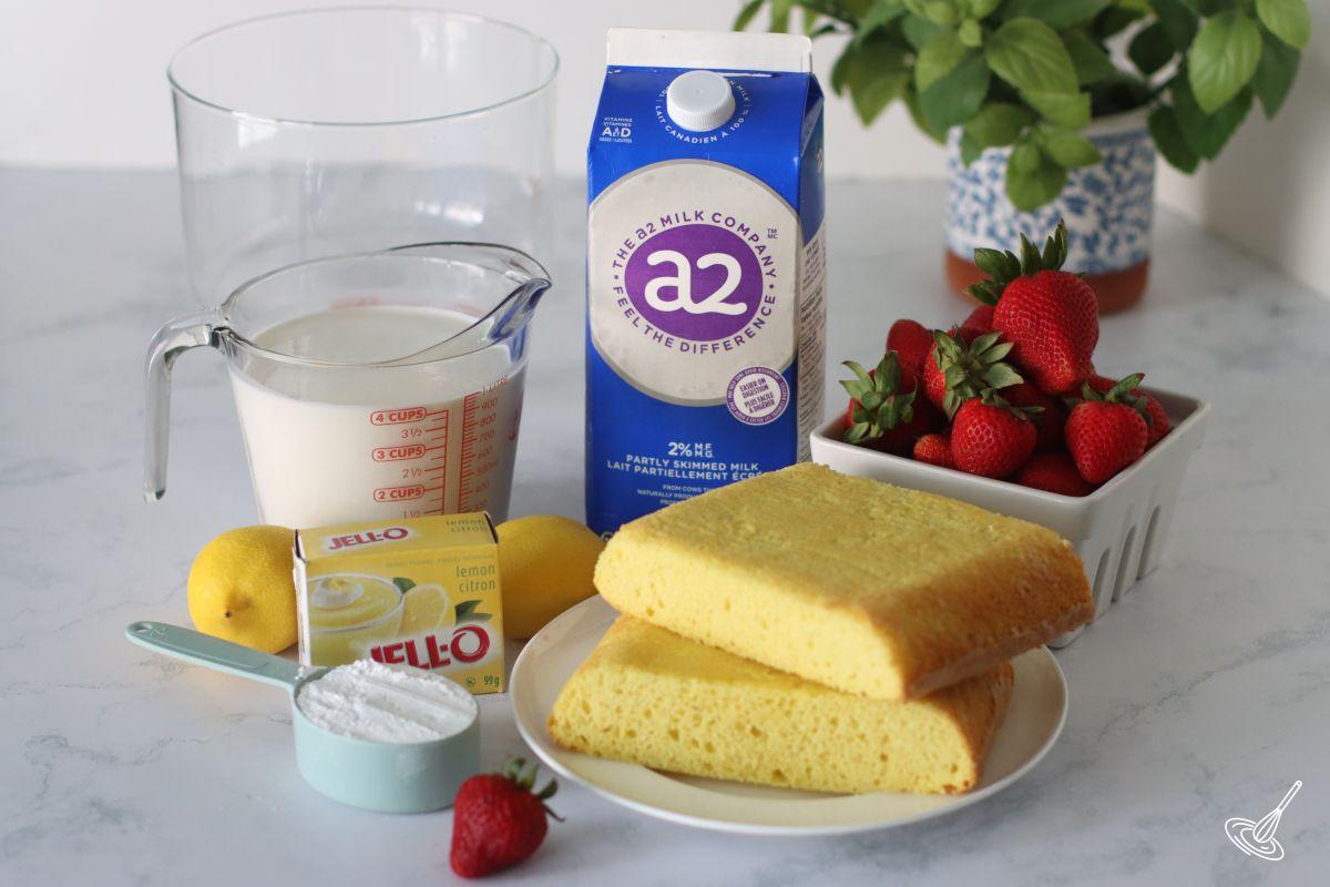 Ingrédients sur le comptoir pour faire un trifle : gâteau au citron, lait, fraises, crème. 