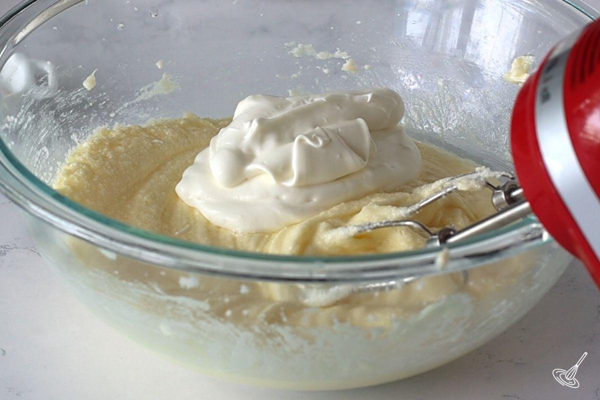 Someone adding Greek yogurt to a bowl of batter. 