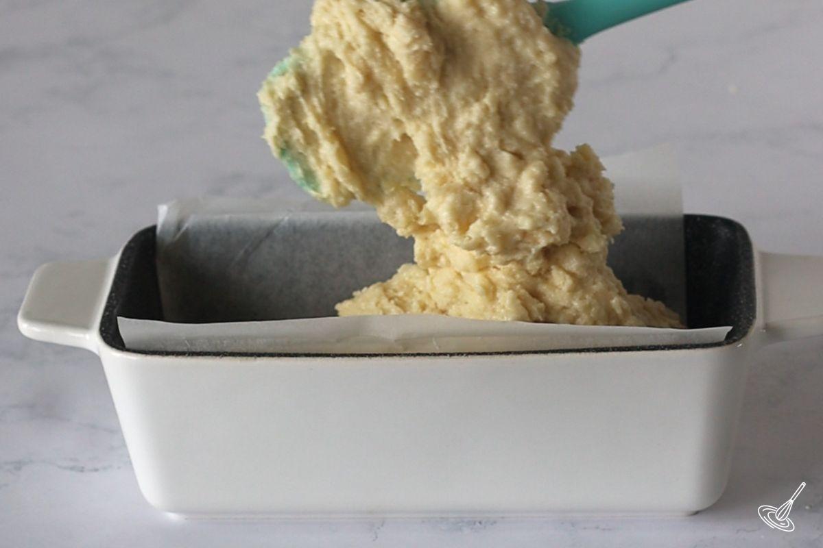 Someone placing Almond Pound Cake batter into a loaf pan. 