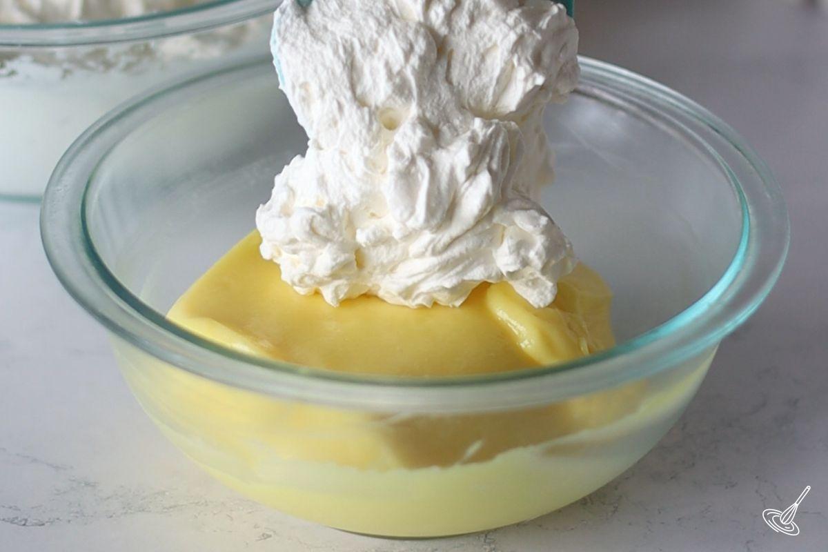 Quelqu'un qui ajoute de la crème fouettée à un bol de pouding au citron préparé. 