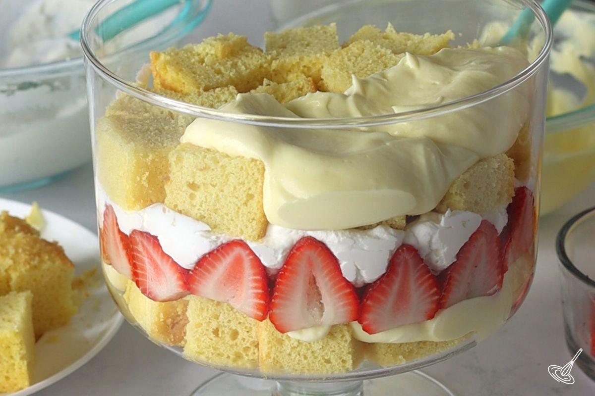 Quelqu'un qui ajoute du pouding au citron sur des cubes de gâteau au citron dans un plat à trifle. 