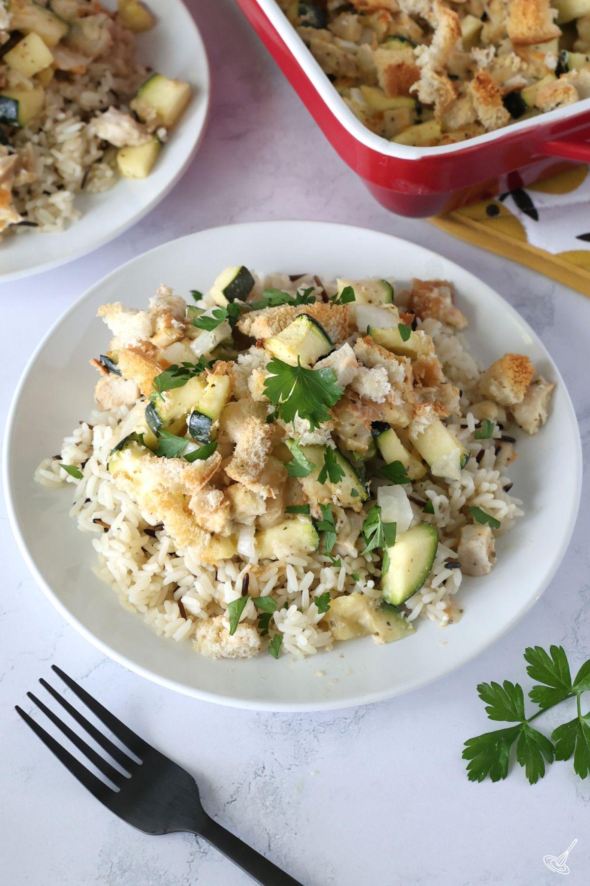 A portion of Chicken and Zucchini Bake over rice on a plate. 