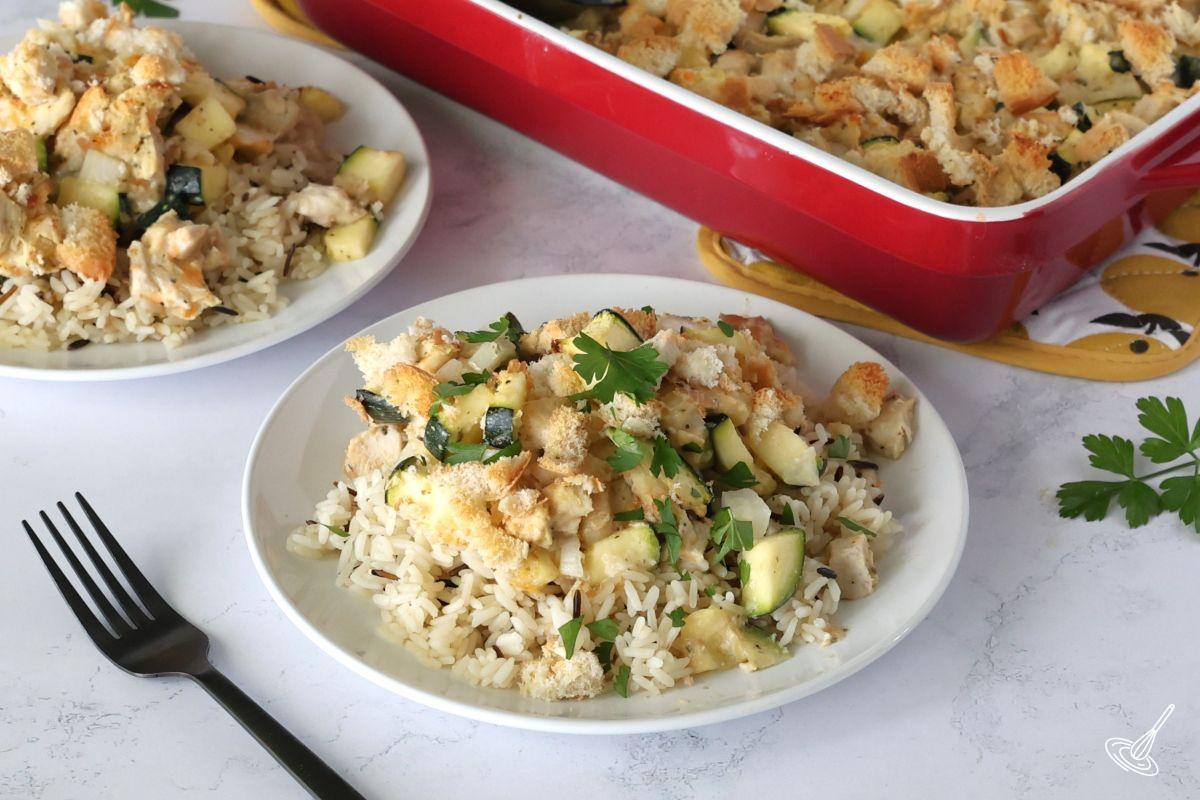 A couple plates of Chicken and Zucchini Bake with a casserole dish.