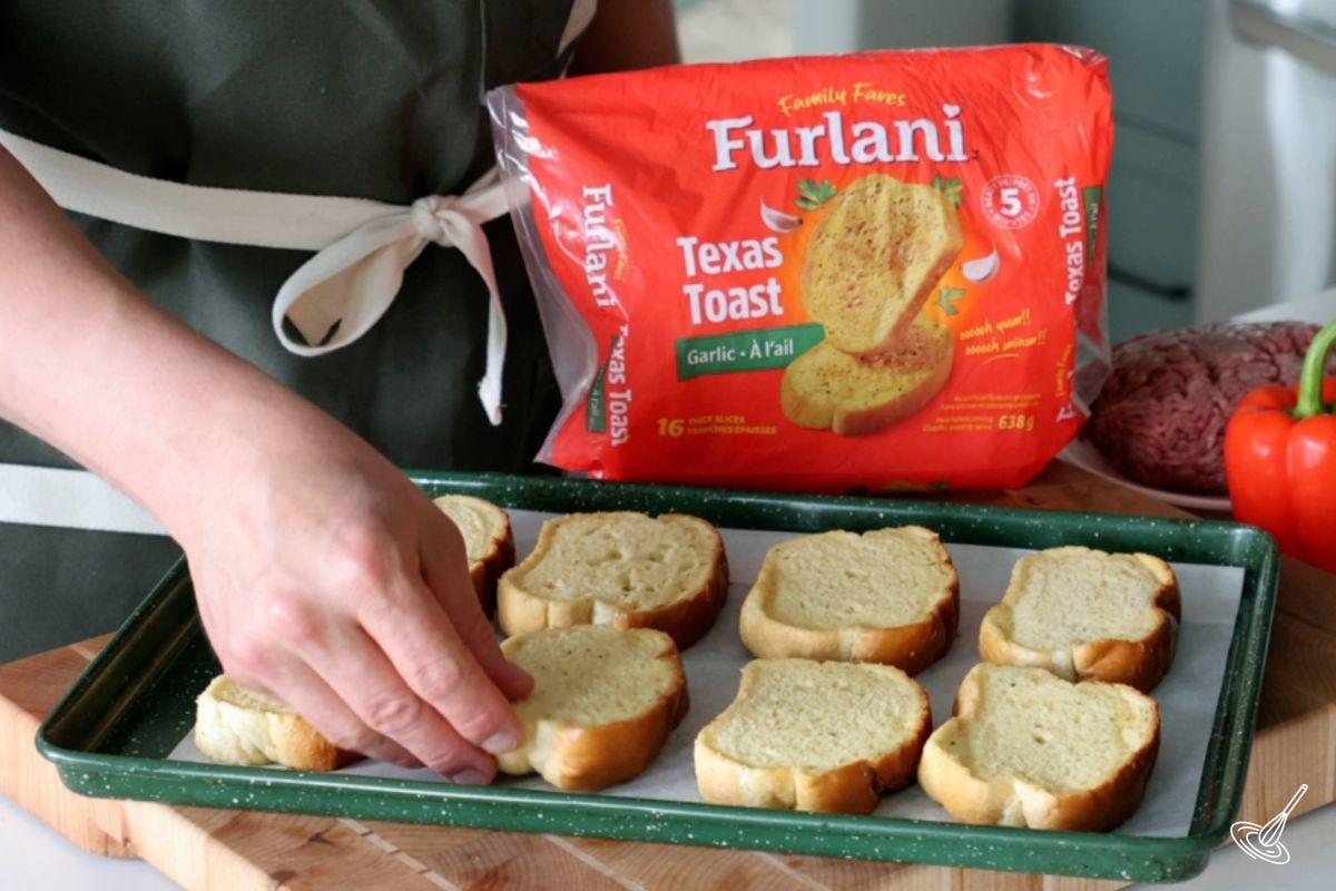 Someone placing texas toast on a baking pan. 