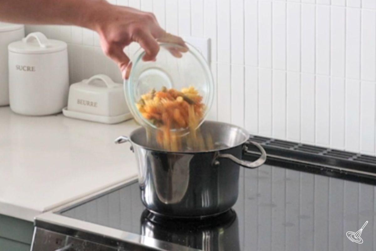 Someone adding pasta to a pot of boiling water.