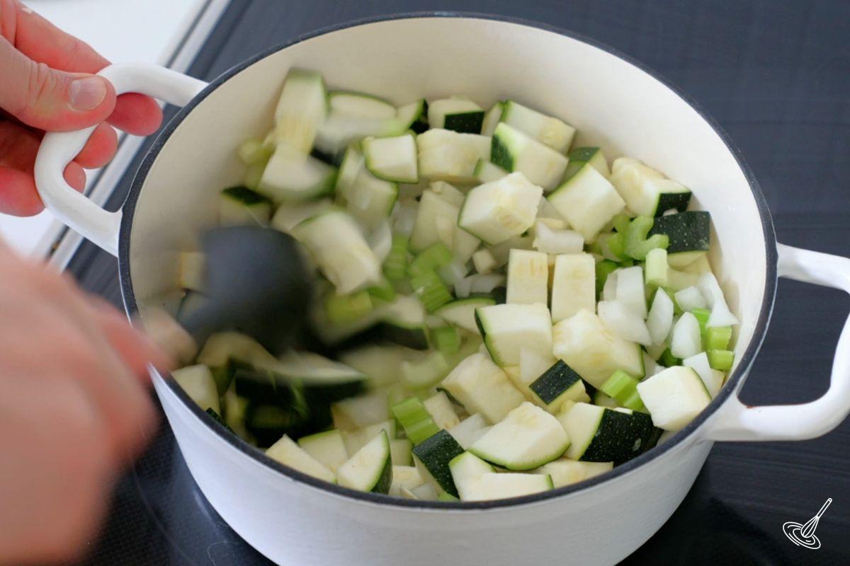 Someone cooking vegetables in a soup pot. 