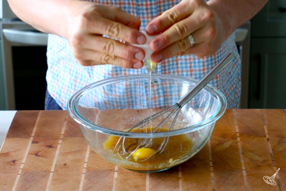 Someone cracking an egg in a glass bowl.