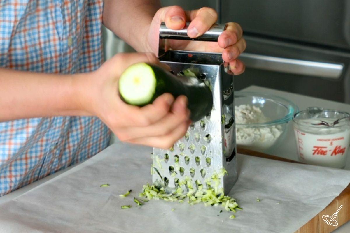 Someone grating a zucchini. 