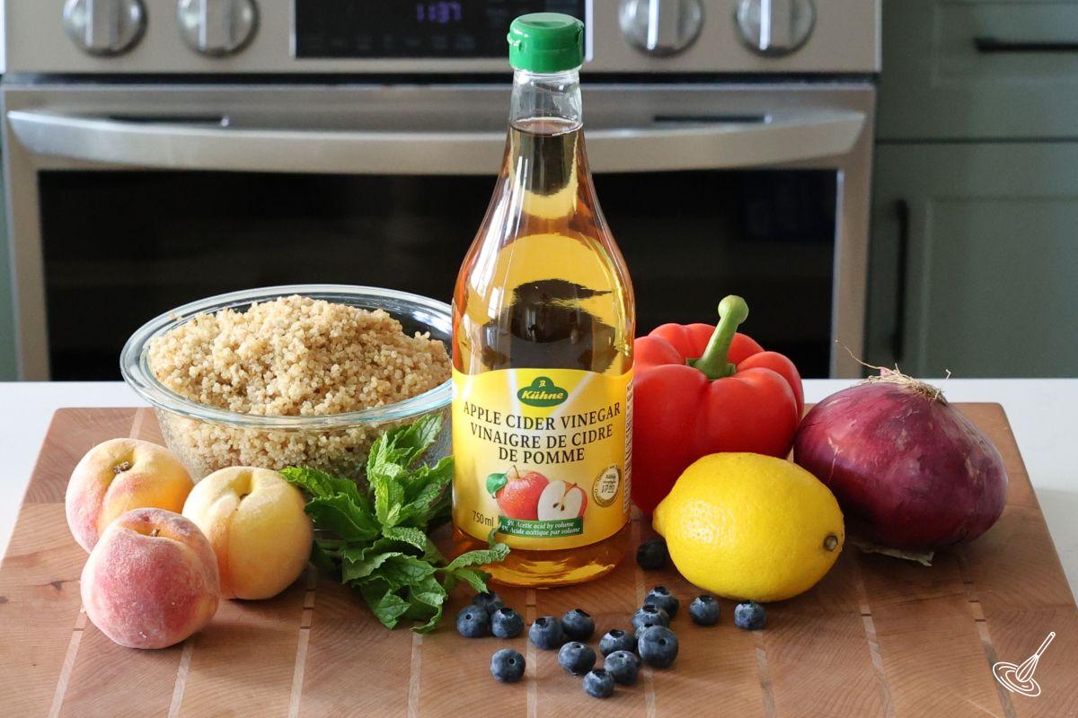 Ingredients on the counter including quinoa, peaches, and vegetables. 