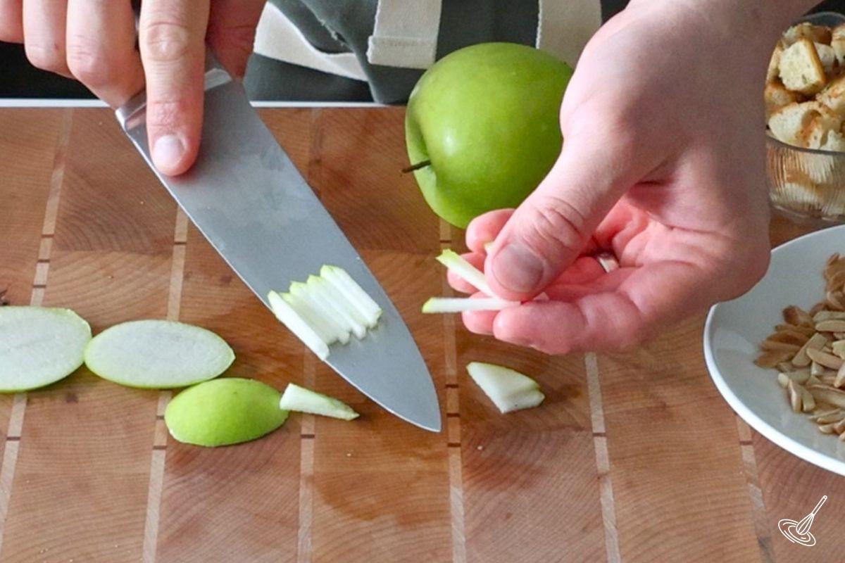 Someone cutting matchstick pieces of apples.