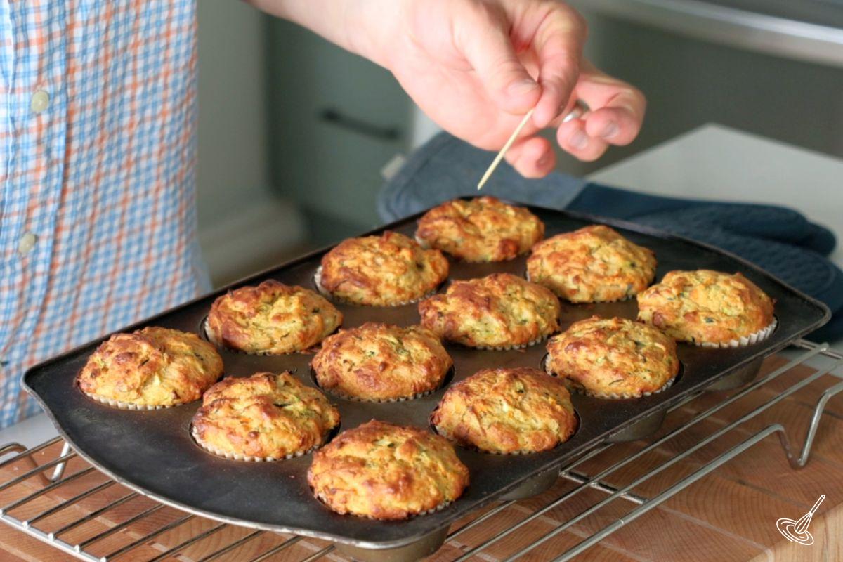 Someone using a toothpick to make sure the muffins are baked.