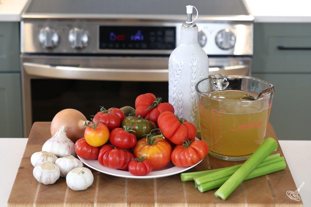A plate of garden tomatoes on a white plate, on a wooden cutting board. 