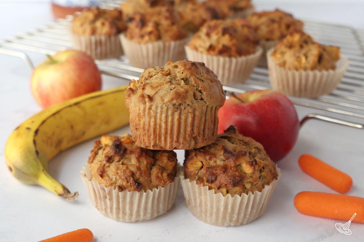 ABC Muffins stacked up on the counter with a cooling rack in the background. 
