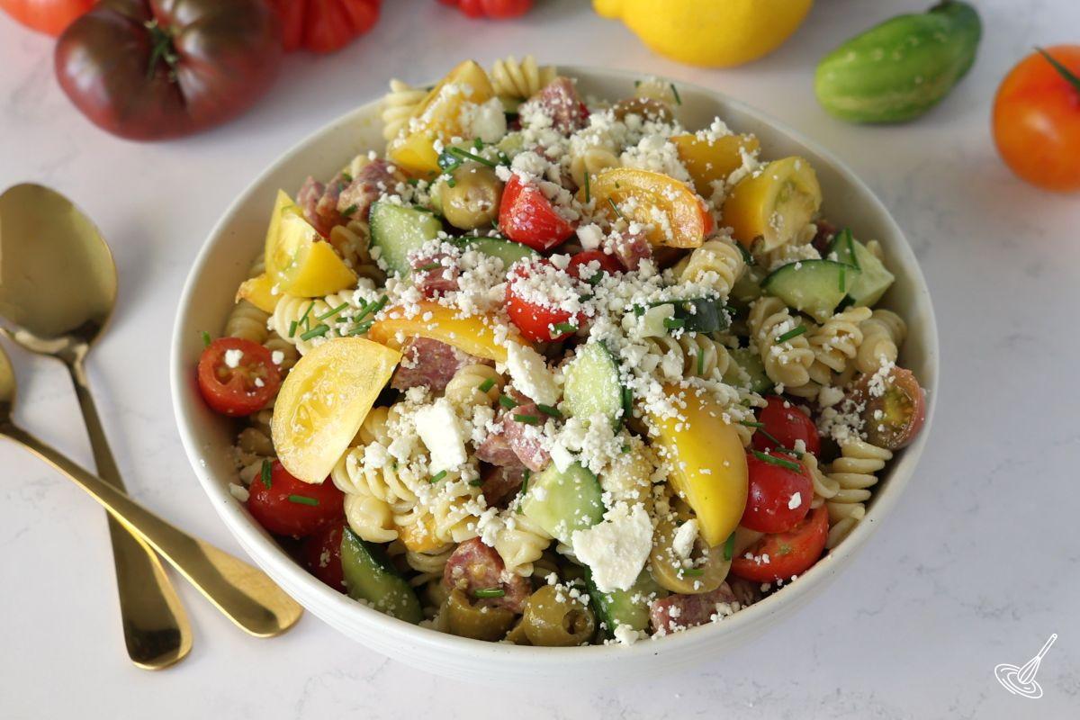 A serving bowl of cucumber tomato pasta salad.