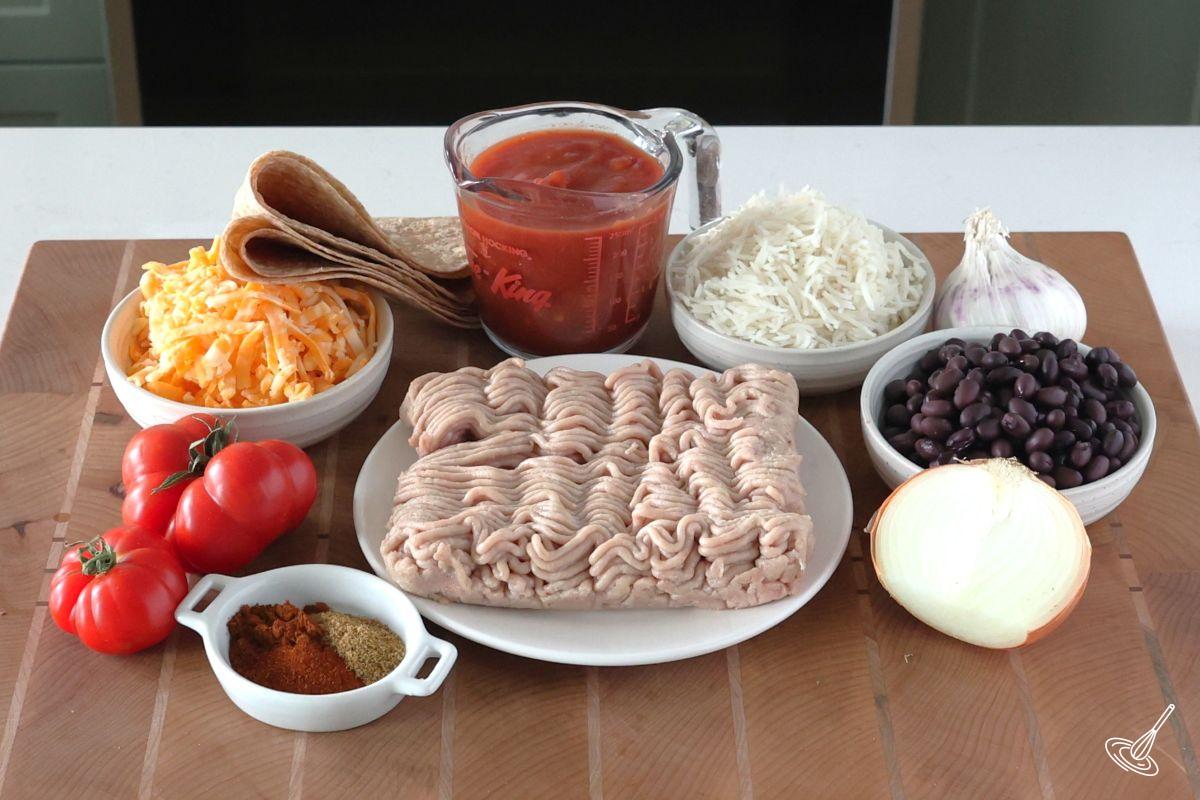 Ingredients on a cutting board including ground turkey, black beans, salsa, and rice.