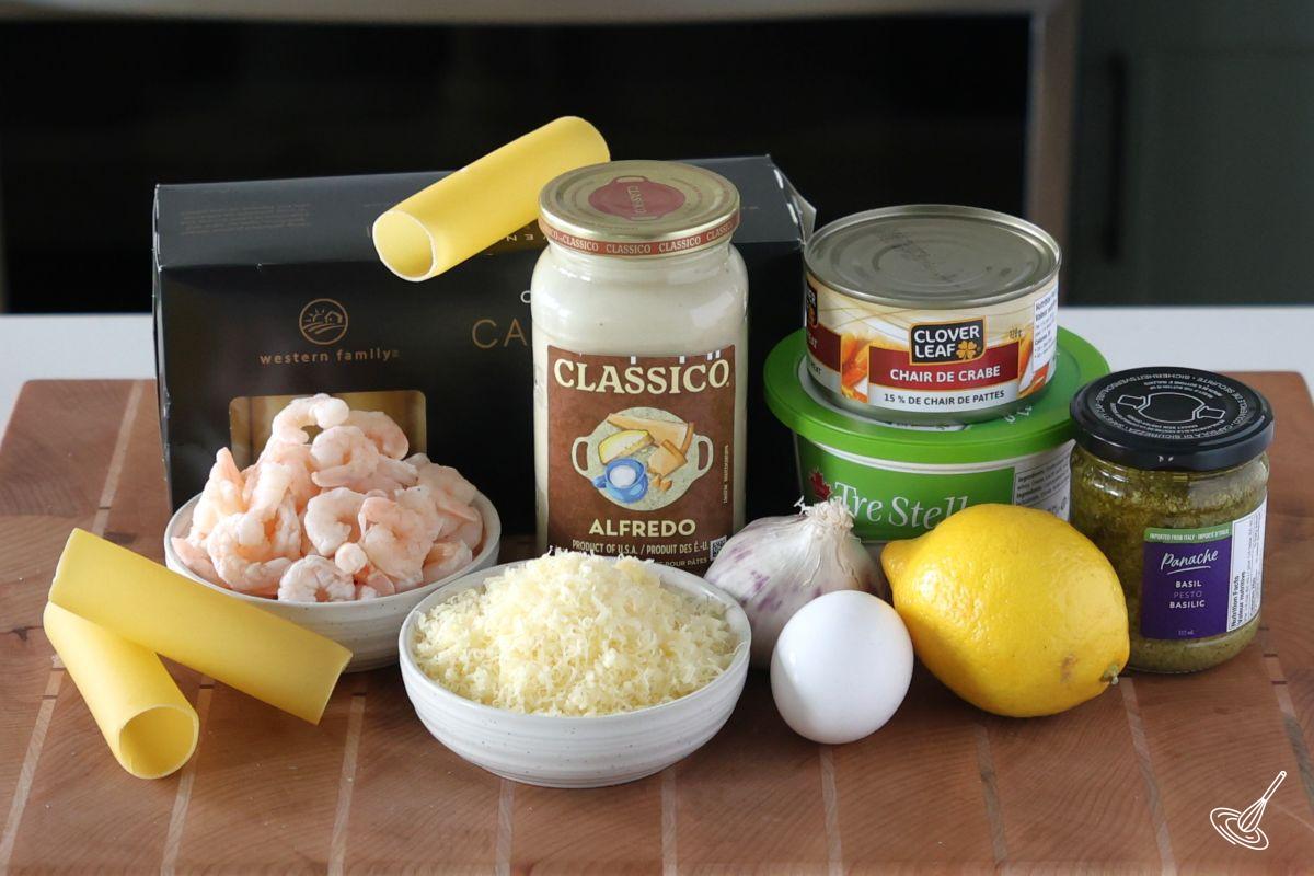 Ingredients on a wooden cutting board including cannelloni shells, shrimp, perso, cheese, and sauce.