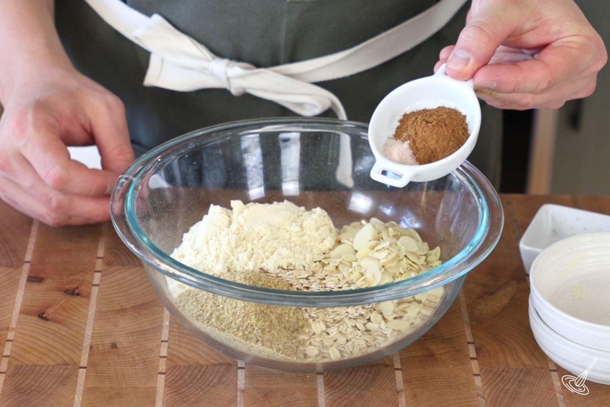 Someone adding cinnamon to a bowl of oats. 