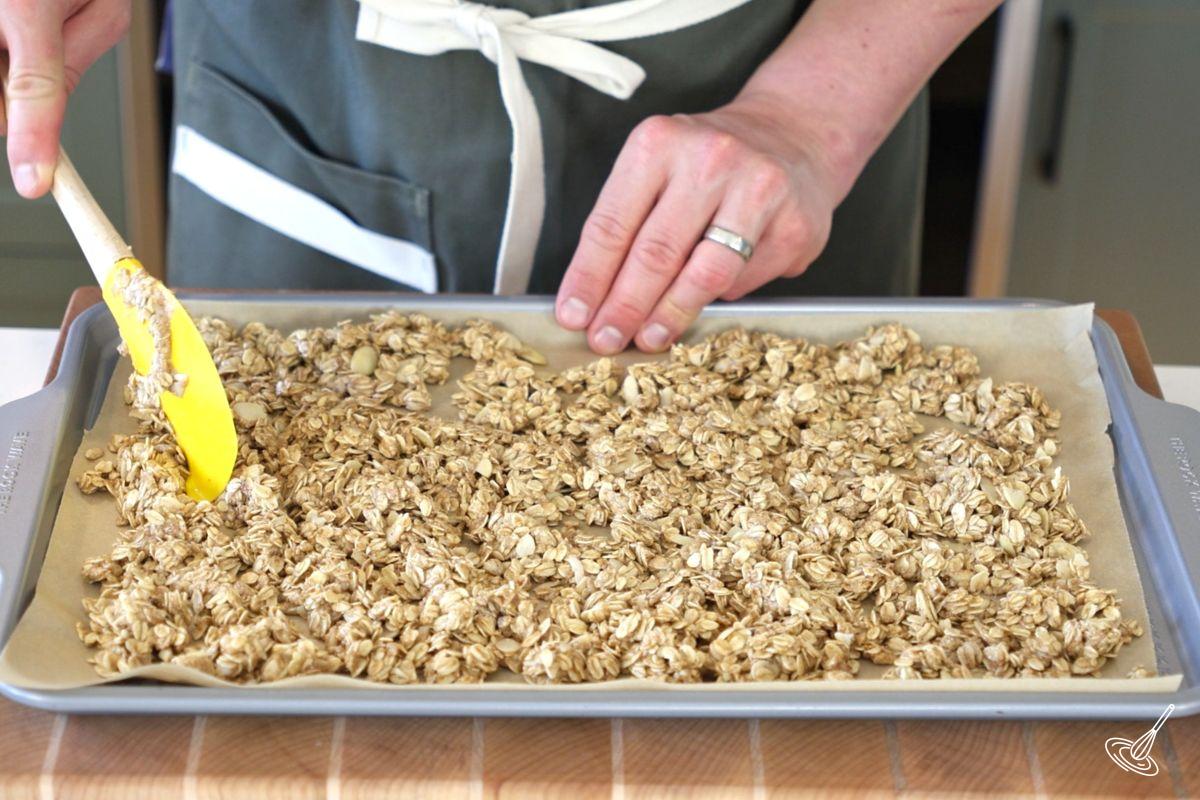 Someone spread a granola mixture on a baking pan.