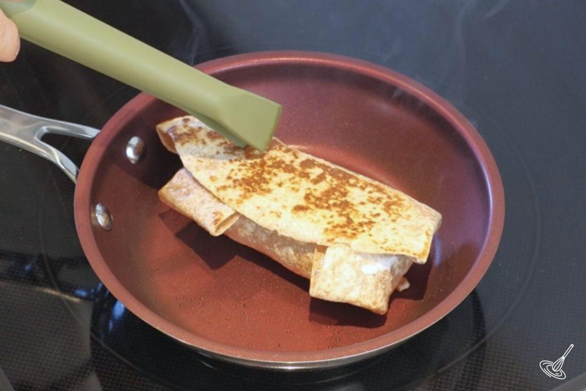 A Ground turkey burrito frying in a pan.