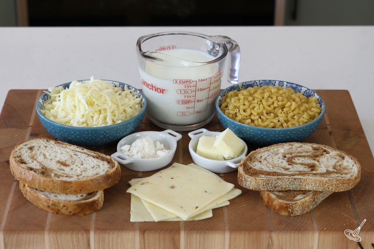 Ingredients on a cutting board, including bread slices, cheese slices, macaroni, and milk. 
